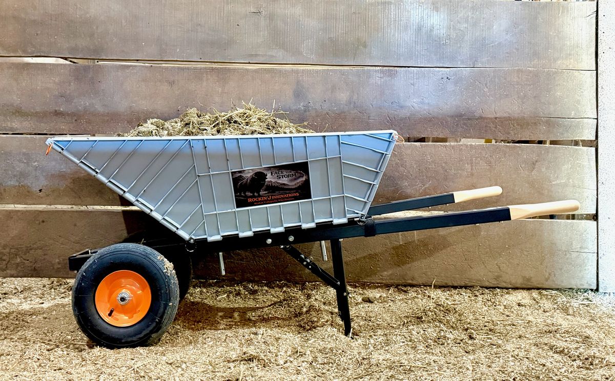 The wheelbarrow loaded with hay in a horse stall