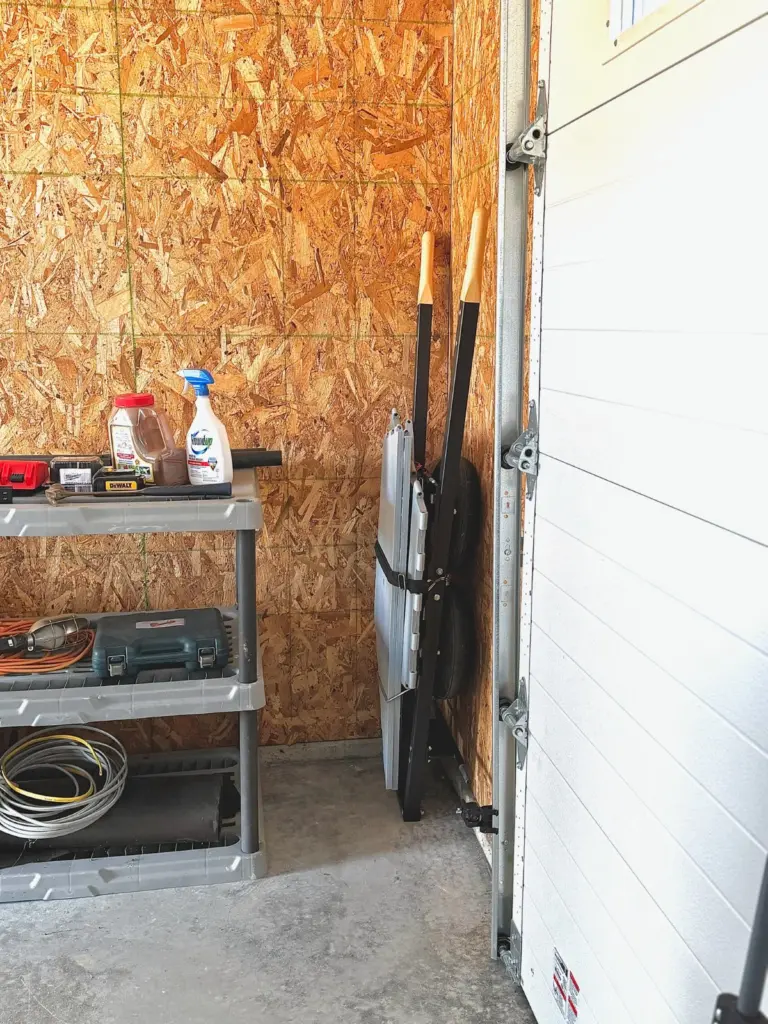 Collapsed and leaned against the garage wall beside the shelving — under 10 inches thick