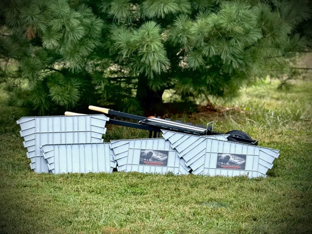 Every part laid out on the grass: the four tub panels, the steel base, the handles, both wheels and the pull-ring rods