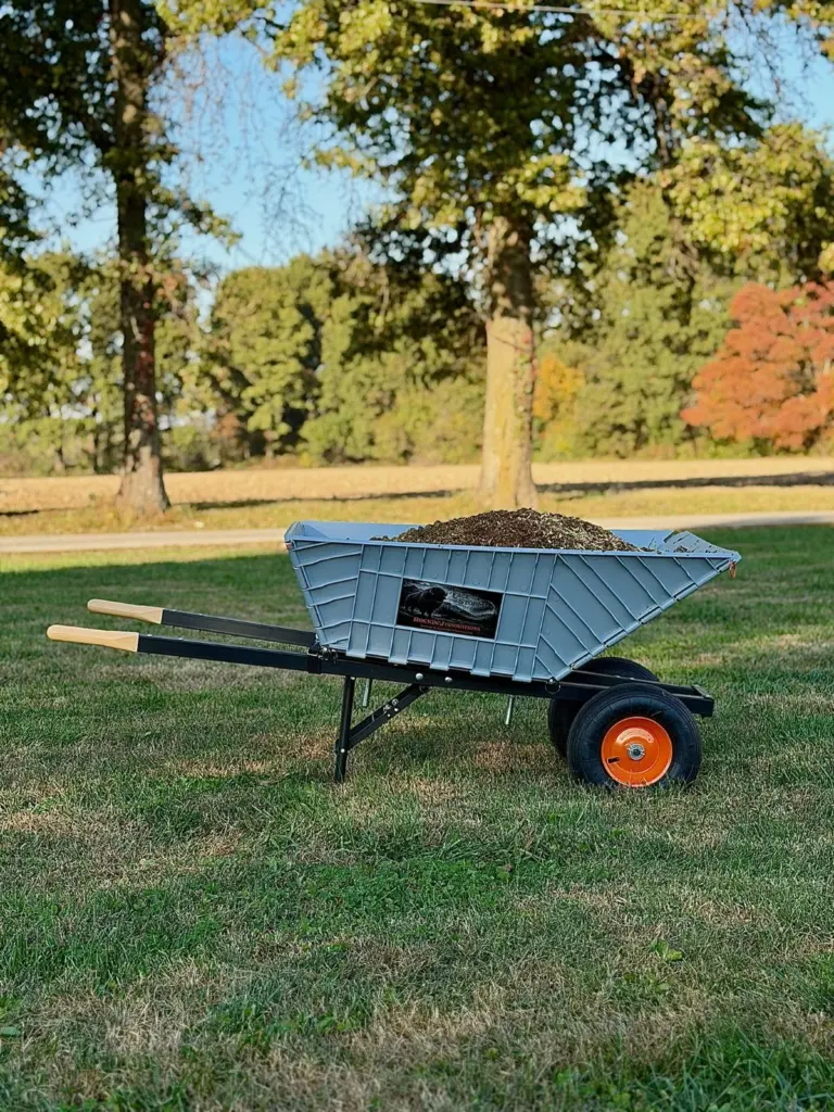 The Workin' Collapsible Wheelbarrow loaded with mulch on a lawn